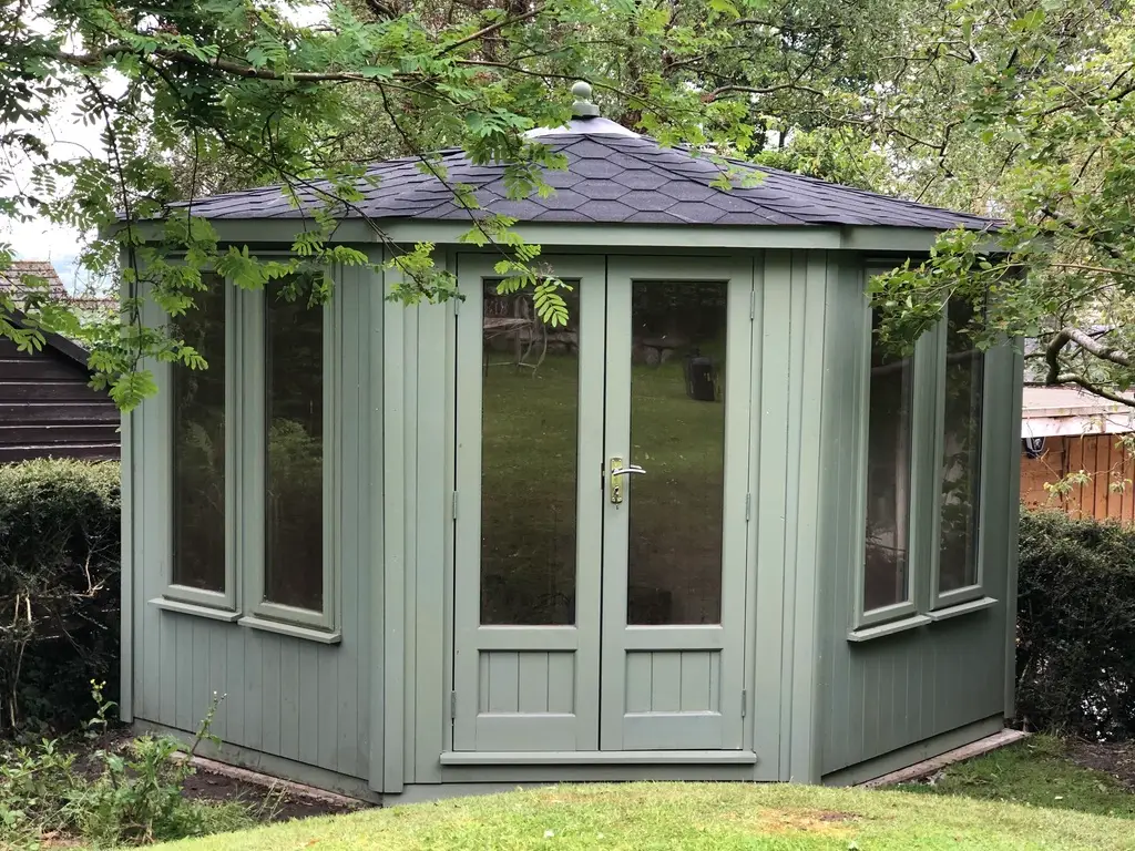 THIS PHOTO SHOWS A CORNER SUMMERHOUSE WITH A VAULTED ROOF WITH KATEPAL FELT TILED FINISH TO ROOF PAINED EXTERIOR
