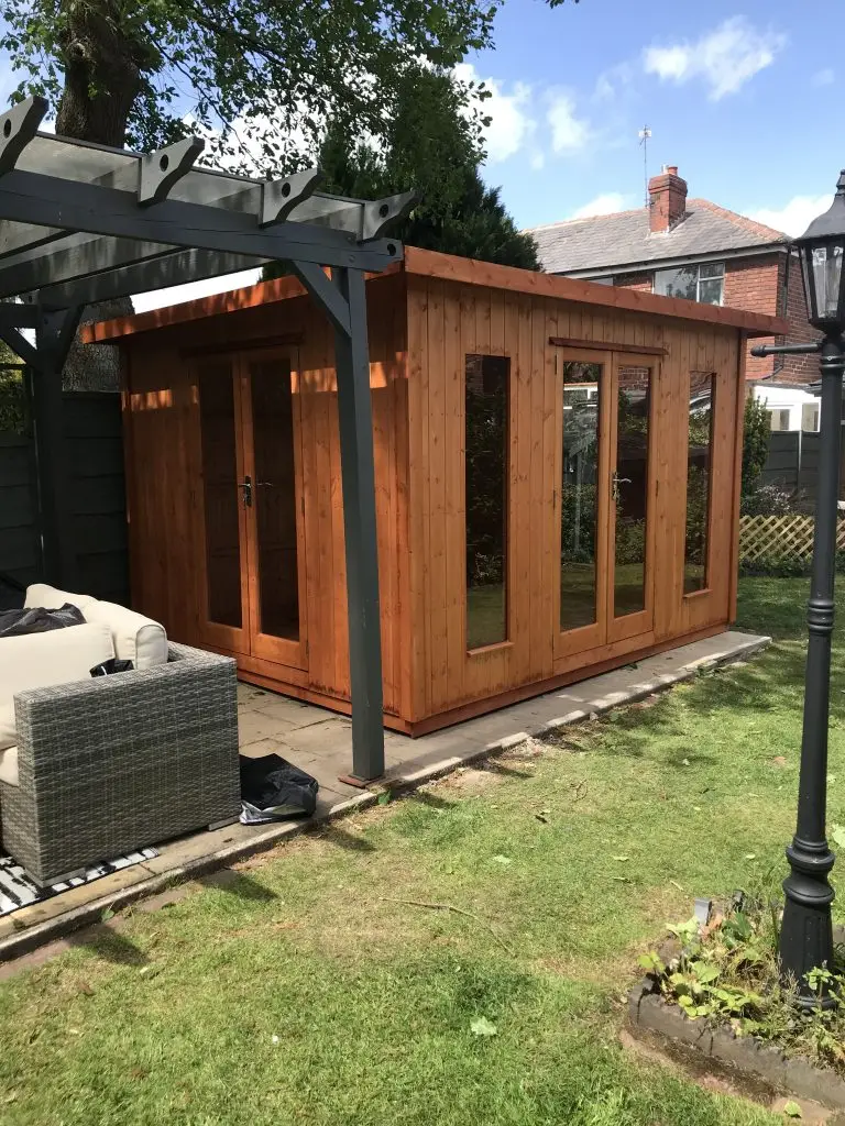 THIS IS A GARDEN ROOM WITH TWO SETS OF DOUBLE DOORS MADE FROM TIMBER